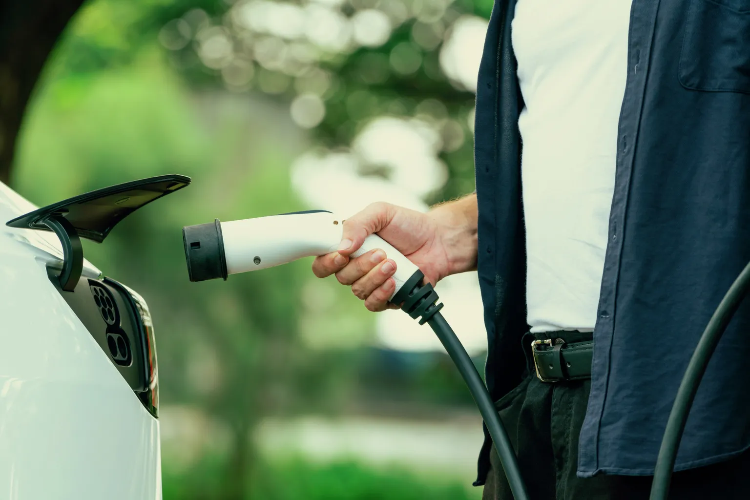 A person plugging a Level 2 charging connector into an EV