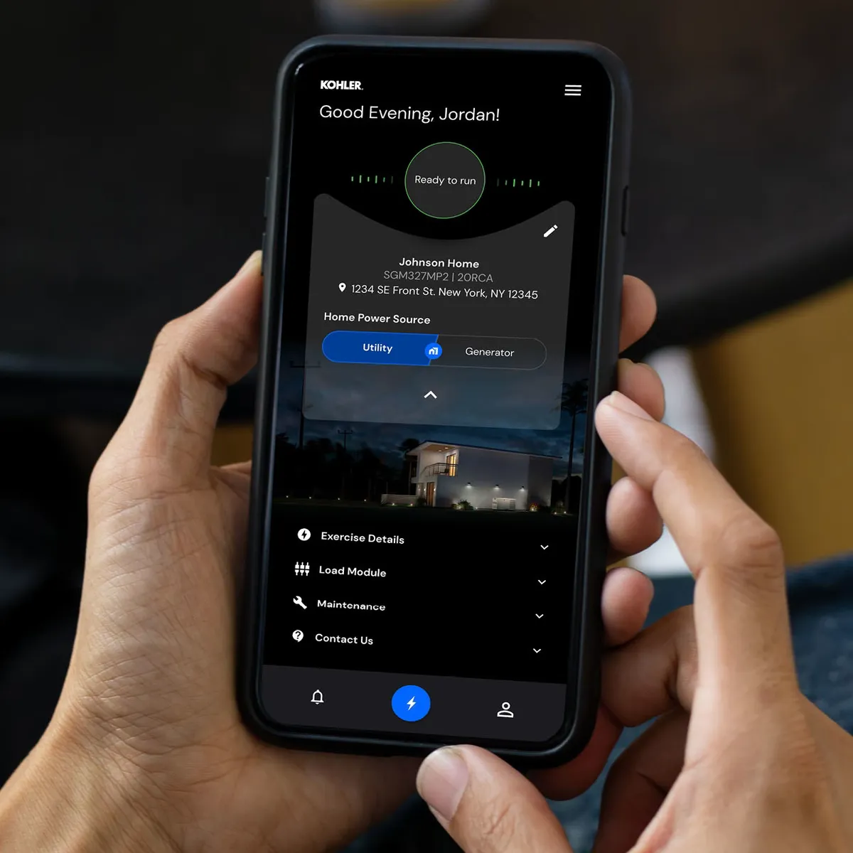 A hand holding a phone displaying the Kohler energy management app